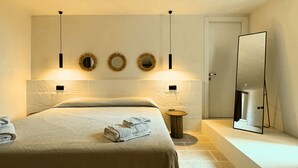A bedroom with a large bed, a bedside table, a mirror, and wall-mounted lights. - Charming masseria fully renovated in 2024  (Monopoli)
