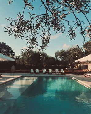 Ein Schwimmbecken mit Liegestühlen und einem überdachten Pergola.