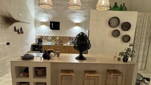 A modern kitchen with a central island, hanging pendant lights, and a rustic ceiling. - Charming masseria fully renovated in 2024  (Monopoli)