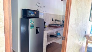 A compact kitchen with a refrigerator, a coffee maker, and a small countertop.