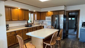 A modern kitchen with wooden cabinets, a central island with bar stools, stainless steel appliances, and a skylight. - "Ackerman Lakeside" - 3 Story, 4 Bed, 3 Bath (South Minnewaukan)