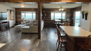 A cozy cabin interior with a living area, a dining space, and a view of the ocean. - "Ackerman Lakeside" - 3 Story, 4 Bed, 3 Bath (South Minnewaukan)