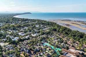 Una località balneare con diverse sistemazioni tipo bungalow, una spiaggia e una vista limpida sull'oceano.