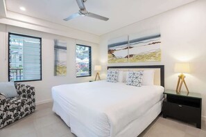 Una camera da letto con un letto grande, un ventilatore a soffitto, un divano e opere d'arte alle pareti.
