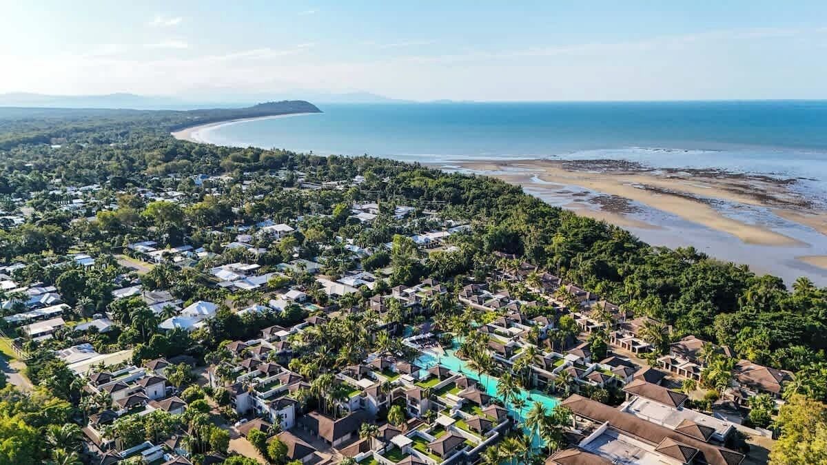 Zona residencial costera con casas, una playa y una extensa masa de agua.