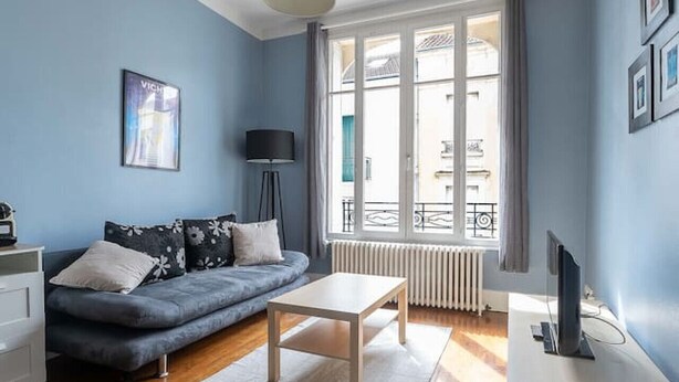 Un saló modern amb un sofà blau, una taula de centre blanca i un moble de televisió.