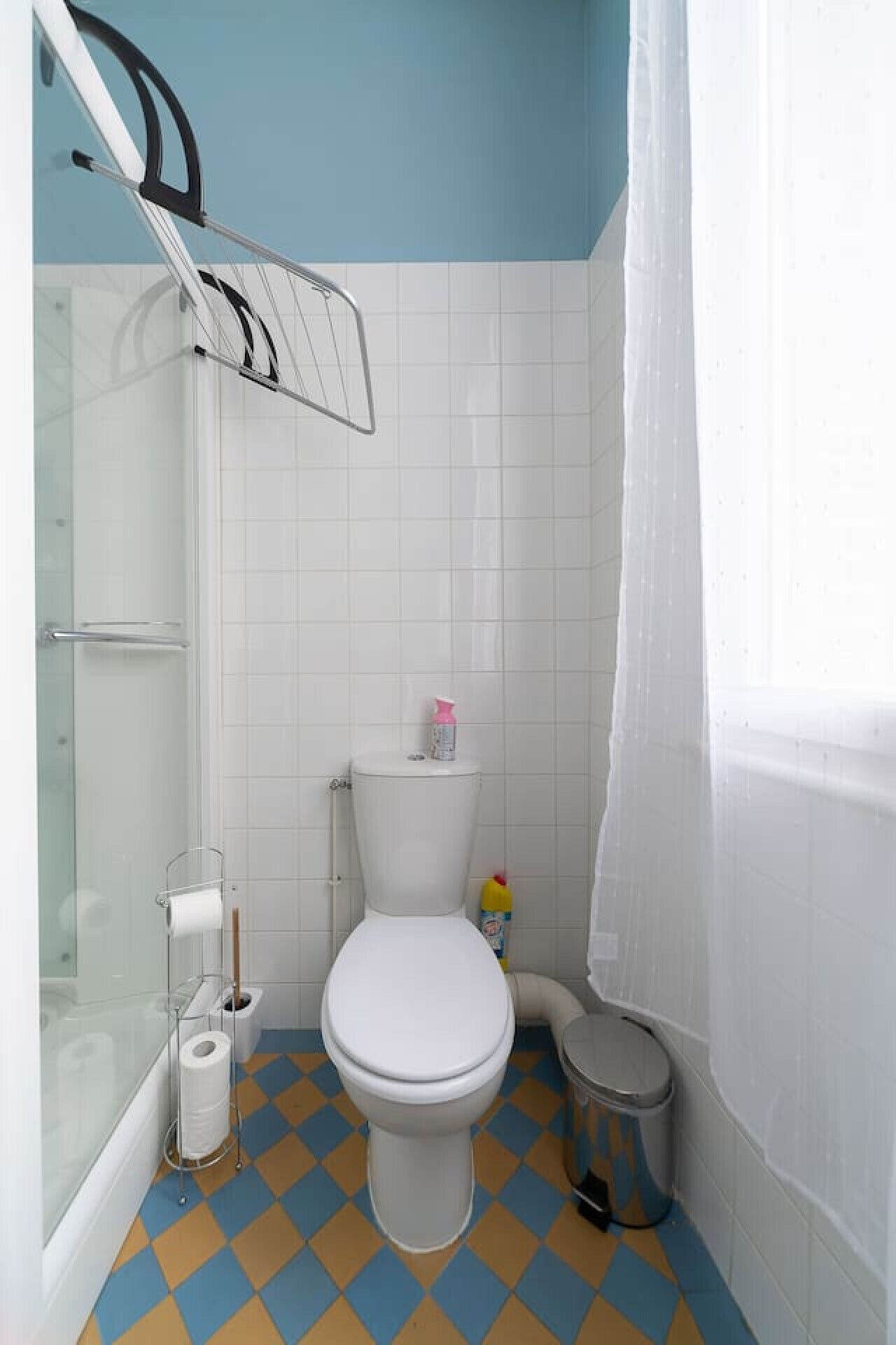 Een badkamer met een wit toilet, een douche en een betegelde vloer.