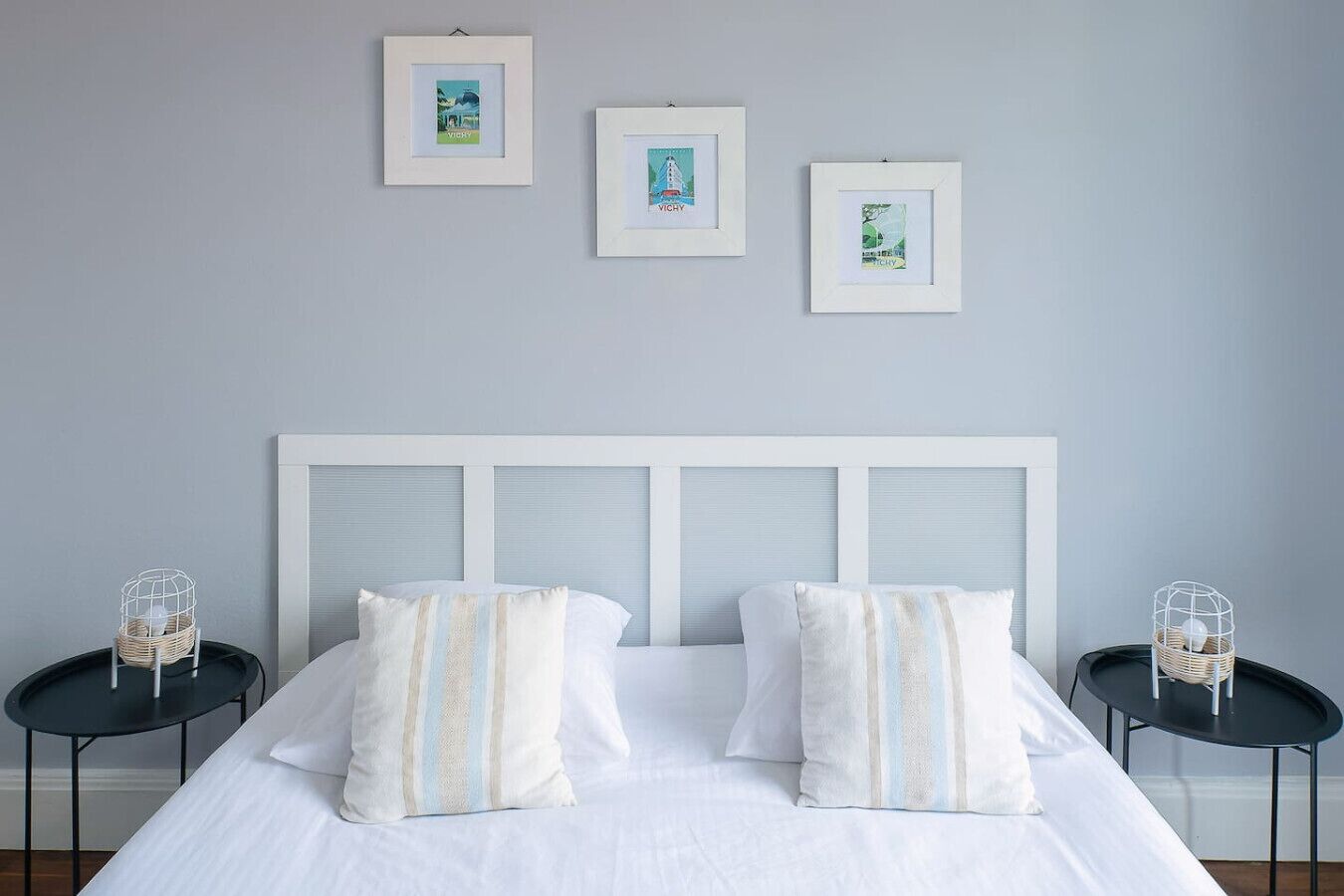 Una camera da letto con un letto, due comodini e tre quadri appesi al muro.