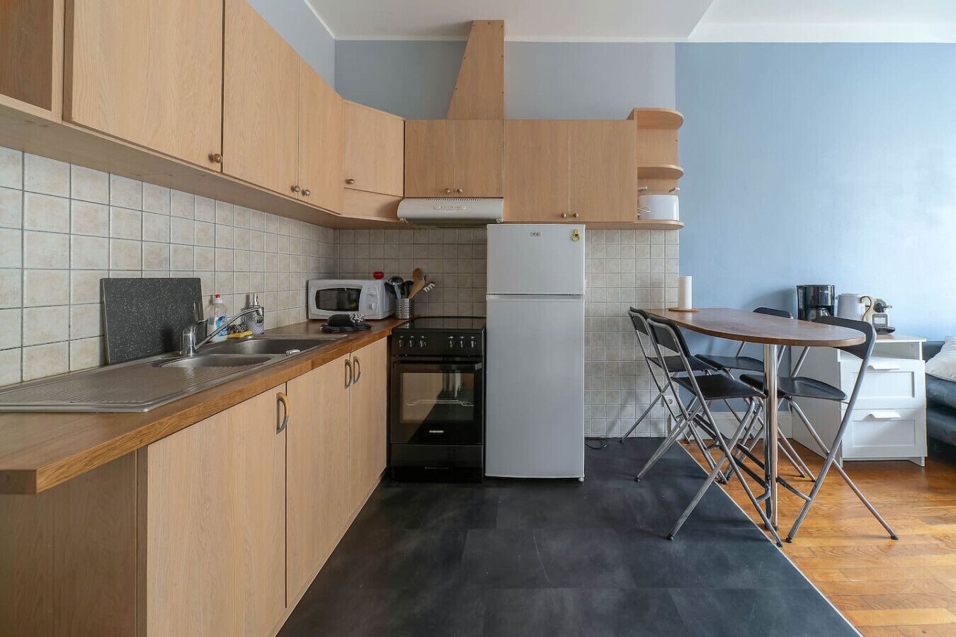 A compact kitchen with wooden cabinets, a microwave, a stove, and a refrigerator.