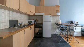 A compact kitchen with wooden cabinets, a microwave, a stove, and a refrigerator.