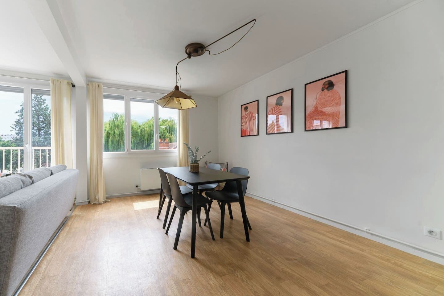 A modern dining area with a table, chairs, and a hanging light fixture.