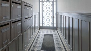 Un corridoio con armadietti su entrambi i lati, un pavimento decorato e una porta con un motivo geometrico.