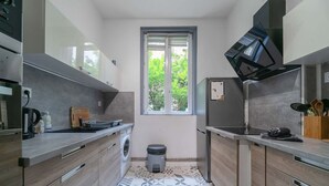Una cucina moderna con mobili grigi, forno integrato e una finestra vista verde.