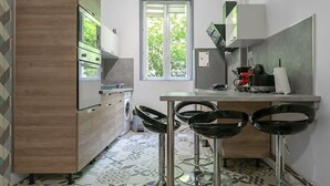 Una cucina moderna con forno integrato, zona pranzo con sgabelli da bar e un'ampia finestra che fa entrare luce naturale.