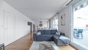 Una sala de estar moderna con un sofá seccional, una mesa de centro de madera y un ventanal con vistas a la calle.