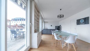 Una cocina moderna con una mesa y sillas de vidrio, un sofá gris y un televisor.