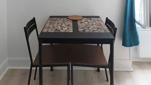 Een eettafel met vier stoelen, een wandklok en een raam met een blauw gordijn.