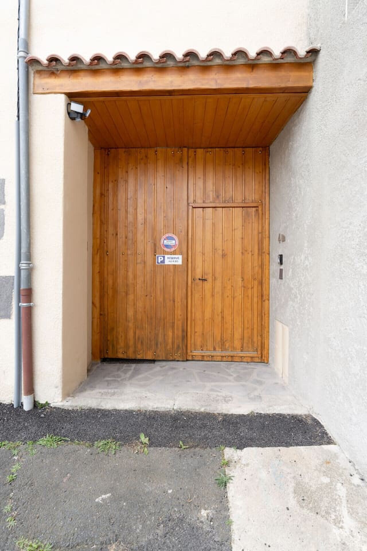A wooden door with a 'No Parking' sign, a small porch, and a concrete step leading to the door.