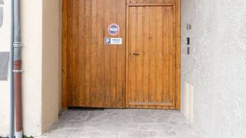 A wooden door with a 'No Parking' sign, a small porch, and a concrete step leading to the door.