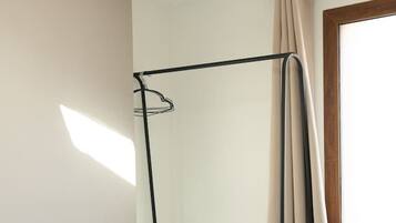 A bunk bed with a wooden ceiling beam, a window with curtains, and a radiator.