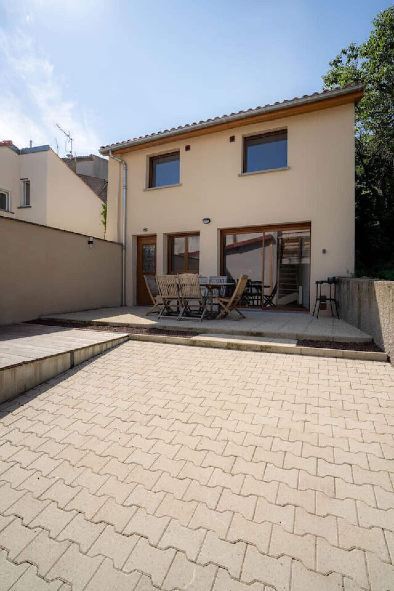 A two-story house with a paved patio and outdoor furniture.