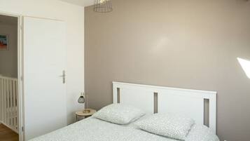 A bedroom with a sloped ceiling, a bed with a white headboard, and a skylight.