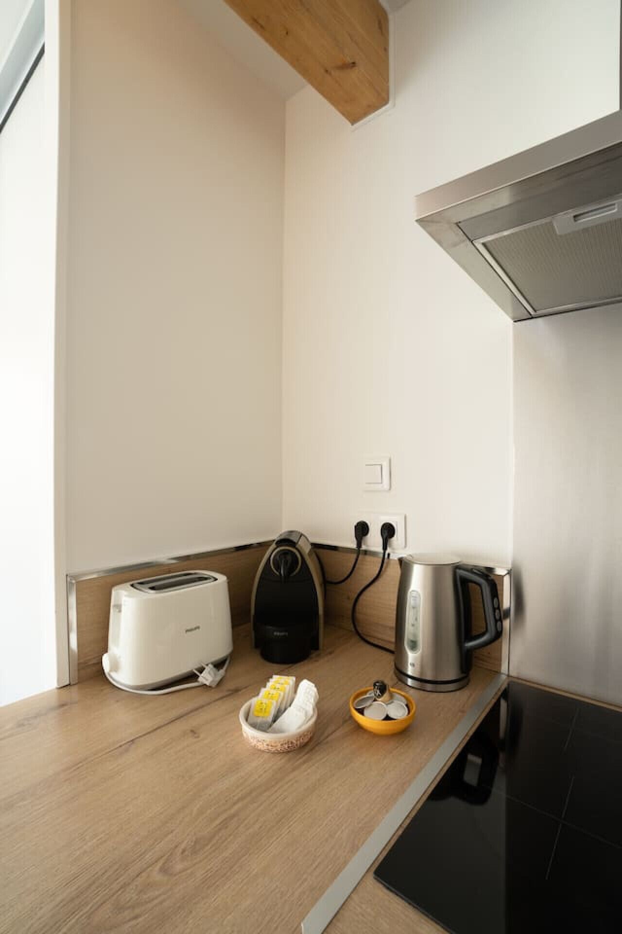 Eine kleine Küchenzeile mit Toaster, Wasserkocher und Kaffeemaschine, sowie eine kleine Schale mit Münzen und einem Teebeutelhalter.