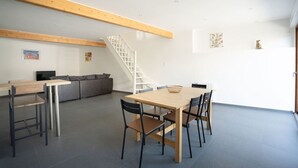 A modern interior with a dining area, a sofa, and a staircase.