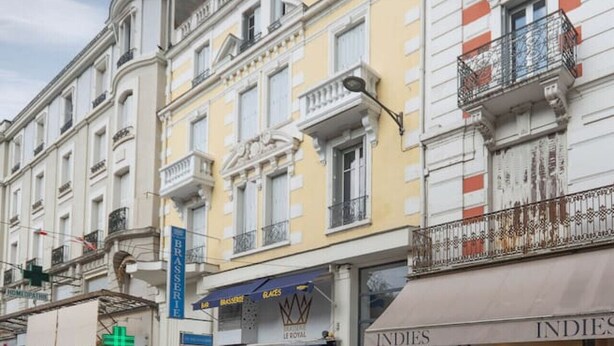 Straßenansicht mit einer Apotheke, einem Café und einem Bekleidungsgeschäft.