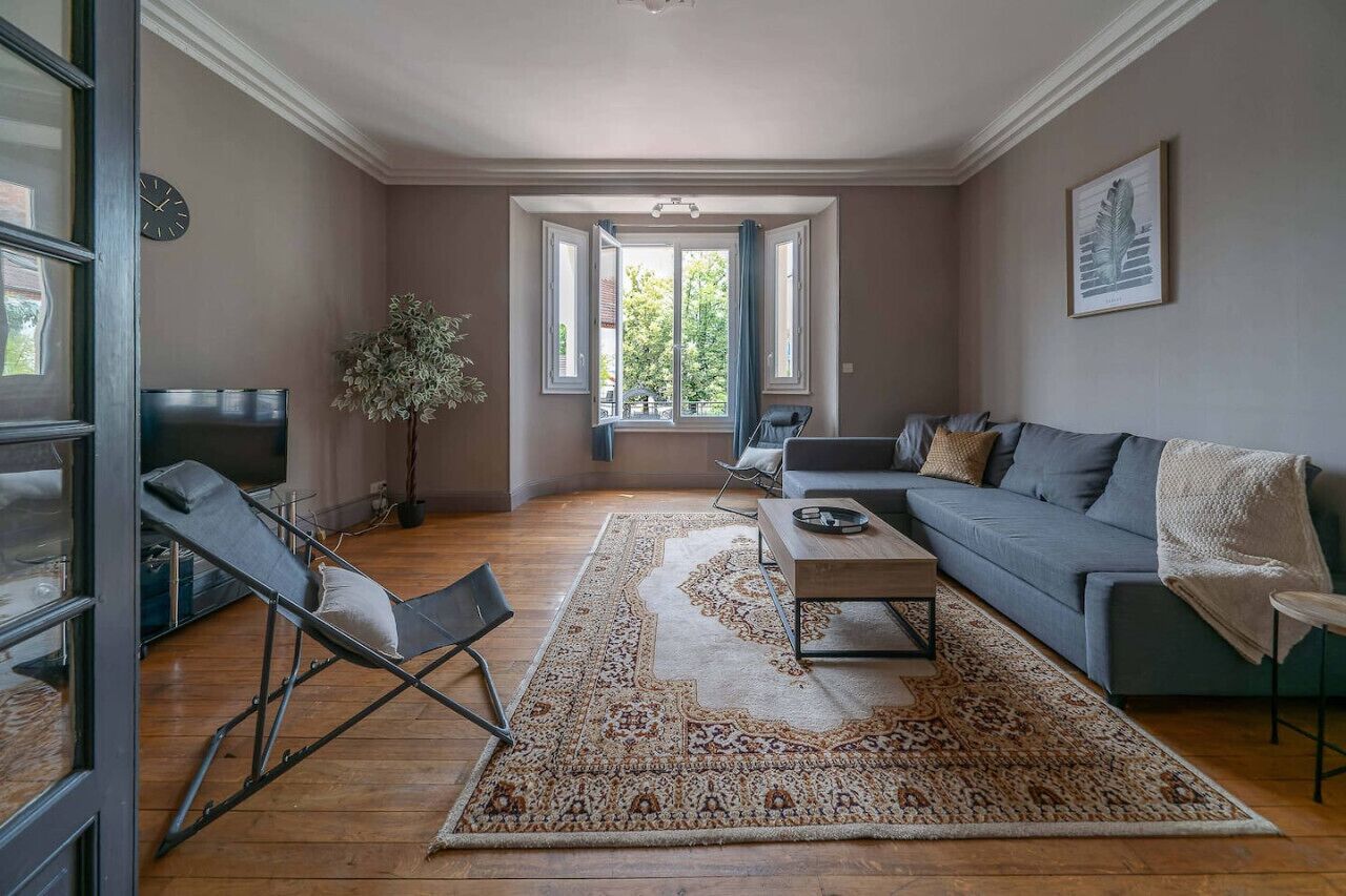 Un salon moderne avec un canapé, une table basse, un téléviseur et une grande fenêtre.