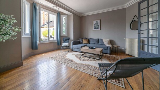 Ein großzügiger Wohnraum mit Sofa, Couchtisch und einem großen Fenster mit Vorhängen.