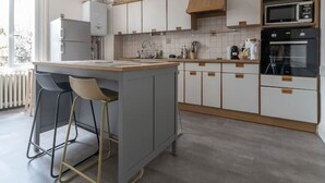 Eine moderne Küche mit einer zentralen Kochinsel, Barhocker, einer Mikrowelle, einem Backofen und einer eingebauten Bücherregal.