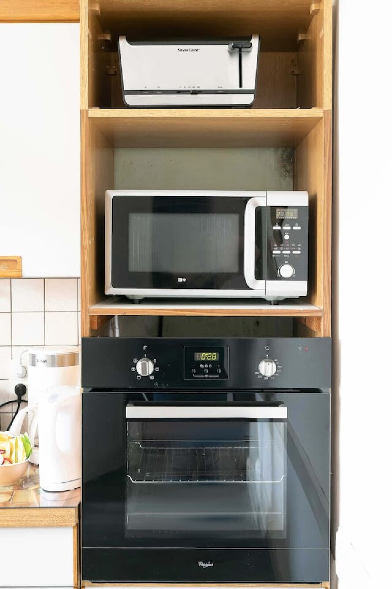 A kitchen with a microwave, oven, and a coffee maker on the counter.