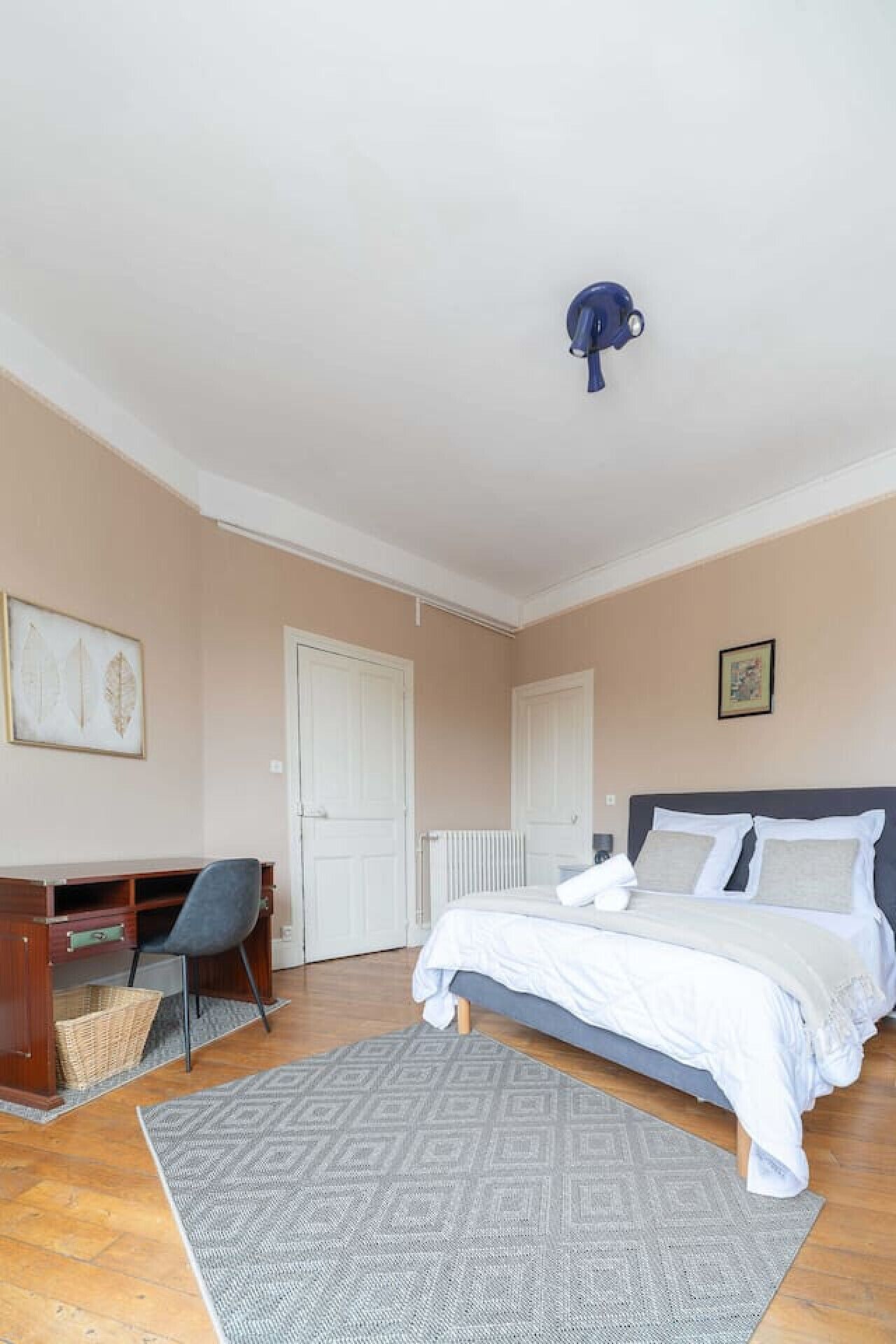 Une chambre à coucher avec un lit, un bureau, une chaise et un radiateur.