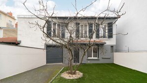 A modern building with a flat roof, a small tree in the center, and a well-maintained lawn. - Appartement design Centre Ville proche Thermes (Vichy)
