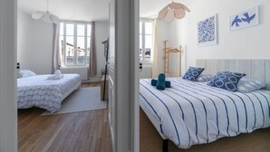 Un dormitorio con dos camas, un radiador, suelo de madera y una ventana con cortinas.