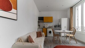 A modern apartment with a living area, kitchenette, and dining space.