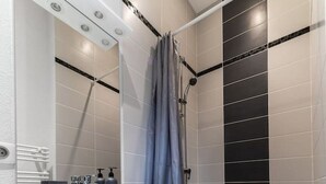 A modern bathroom with a white vanity, a shower with a curtain, and a bathtub with a towel.