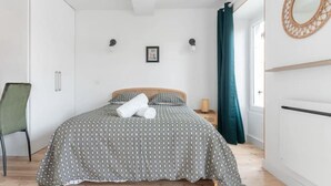 Een slaapkamer met een bed, een stoel, een spiegel en een raam met gordijnen.