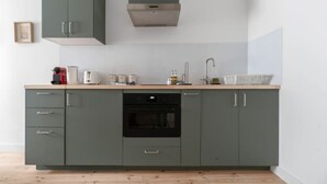 Een keuken met grijze kastjes, een ingebouwde oven en een roestvrijstalen afzuigkap.