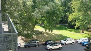 Vista de un aparcamiento con coches, un paso de peatones y árboles al fondo.