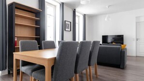 Una sala de estar moderna con una mesa de comedor, sillas, un sofá y un televisor.