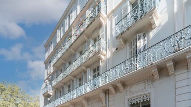 Un edificio de varios pisos con balcones, ventanas grandes y un cielo despejado.
