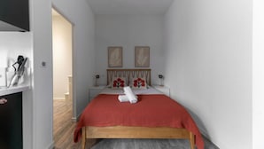 Een slaapkamer met een houten bed, een rode deken en twee nachtkastjes aan de muur met lampen.