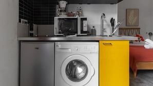 Een praktische keuken met een wasmachine, magnetron en koffiezetapparaat.
