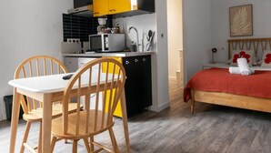 Een kleine kamer met een eethoek, kitchenette en een bed.
