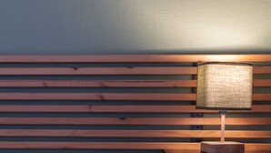 A bed with a red pillow, a wooden headboard, and a bedside lamp.