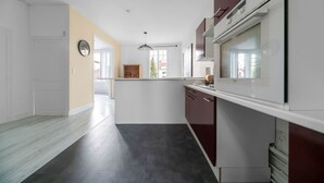 A modern kitchen with white and dark wood cabinets, a built-in oven, and a large window providing natural light.