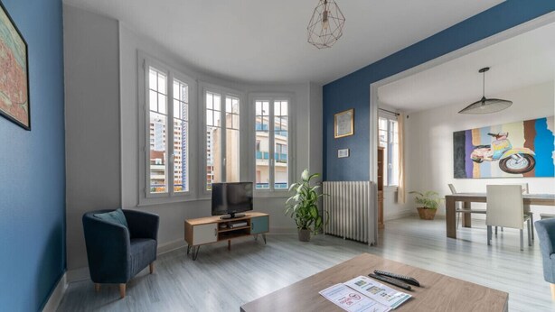 A modern living room with a flat-screen TV, a wooden coffee table, and a blue sofa.