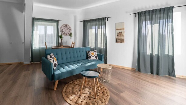 Un salon moderne avec un canapé bleu, une table basse ronde et une petite table d’appoint.